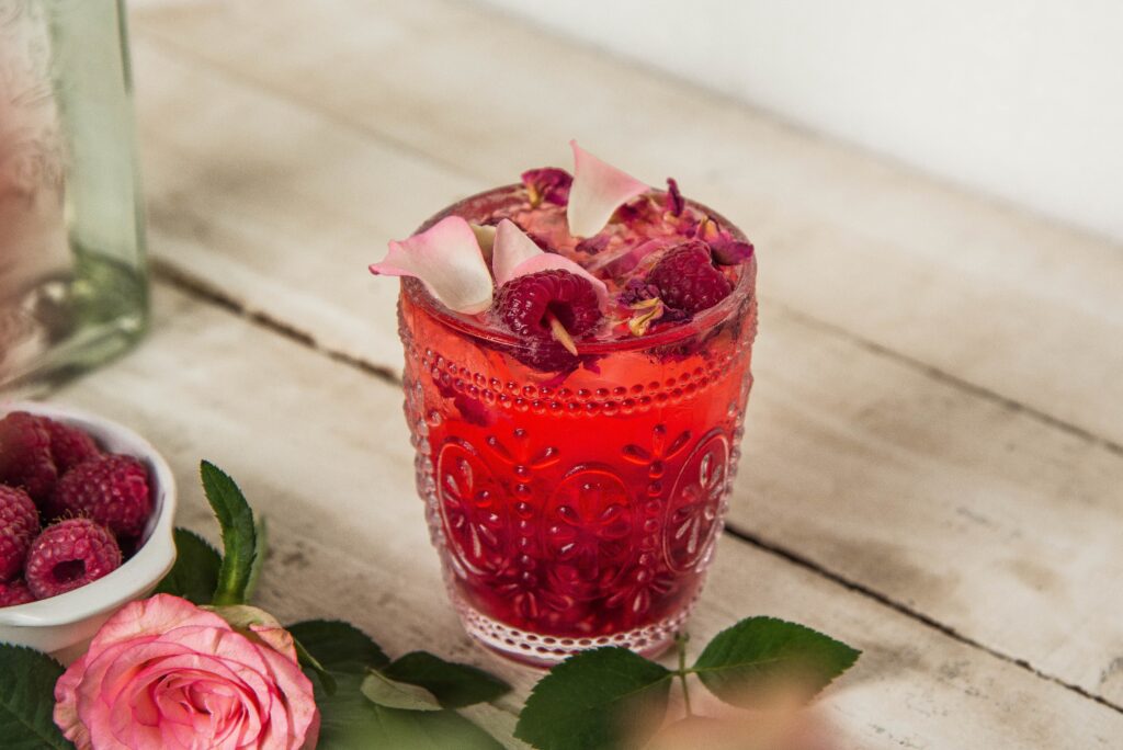 closeup shot glass with raspberry lemonade with dried flowers