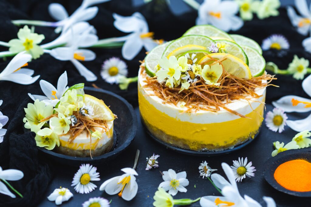 raw vegan cake with lemon lime black surface covered with tiny daisy flowers